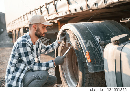 Testing the tires. Young truck driver is with his vehicle at daytime Testing the tires. Young truck driver is with his vehicle at daytime 124631853