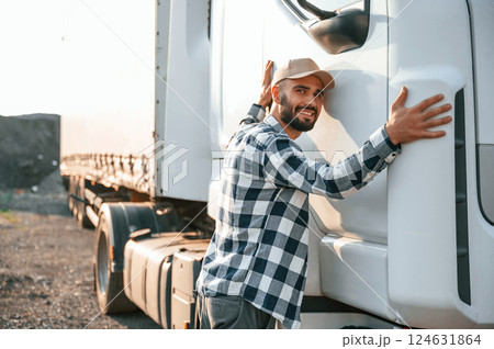 Embracing his vehicle. Young truck driver is outdoors at day time 124631864