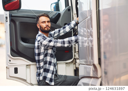 Opening the door. Young truck driver is with his vehicle at daytime 124631897