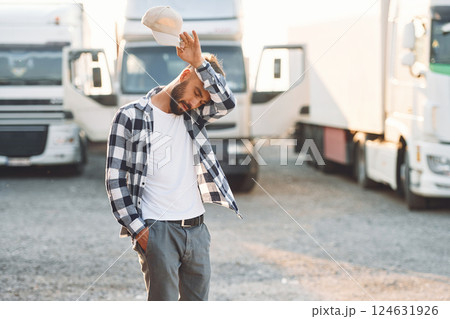 Tired, walking outside. Young truck driver is with his vehicle at daytime 124631926