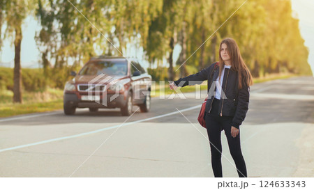A young girl stands on the road and tries to stop any car. A young girl stands on the road and tries to stop any car. 124633343