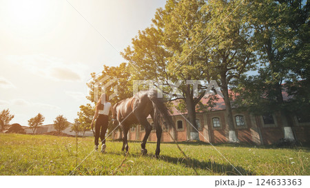The girl walks with her beloved horse on a summer day. 124633363