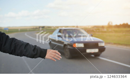 A young girl stands on the road and tries to stop any car. 124633364