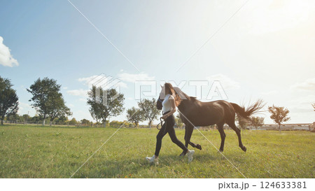 The girl runs next to a horse in the summer on the meadow. The girl runs next to a horse in the summer on the meadow. 124633381