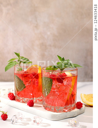 Cold homemade lemonade cocktail, mojito with mint, raspberry and fruits on a sunny table, refreshing summer drink recipe, detox diet and weight loss concept, restaurant menu 124633418