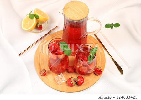 Strawberry iced tea or mint lemon cocktail, refreshing summer drink recipe. Glasses with berry lemonade on a light concrete table, detox diet and weight loss concept, restaurant menu. Strawberry iced tea or mint lemon cocktail, refreshing summer drink recipe. Glasses with berry lemonade on a light concrete table, detox diet and weight loss concept, restaurant menu. 124633425