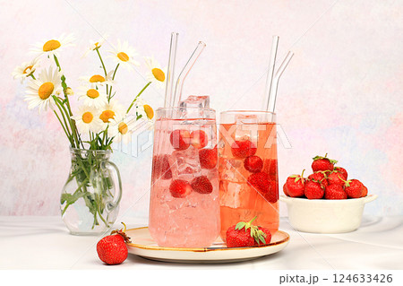 Strawberry iced tea or mint lemon cocktail, refreshing summer drink recipe. Glasses with berry lemonade on a light concrete table, detox diet and weight loss concept, restaurant menu. Strawberry iced tea or mint lemon cocktail, refreshing summer drink recipe. Glasses with berry lemonade on a light concrete table, detox diet and weight loss concept, restaurant menu. 124633426