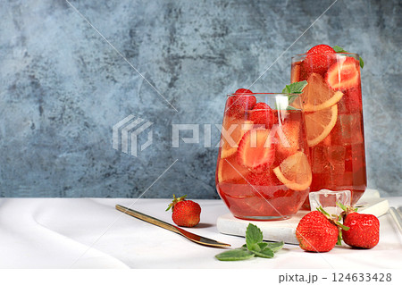 Strawberry iced tea or mint lemon cocktail, refreshing summer drink recipe. Glasses with berry lemonade on a light concrete table, detox diet and weight loss concept, restaurant menu. 124633428