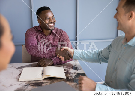 Two businessmen accomplishing formal meeting in office with handshake gesture Two businessmen accomplishing formal meeting in office with handshake gesture 124633907