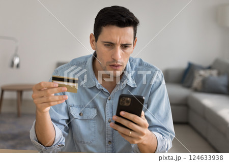 Man holds phone and card, getting problems with online payment 124633938