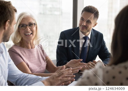 Young and mature businessmen and businesswomen engaged in friendly talk 124634009