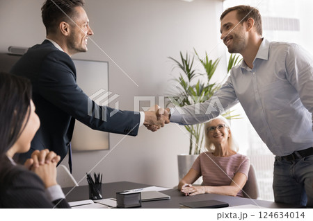 Two business partners shaking hands during formal meeting in boardroom 124634014