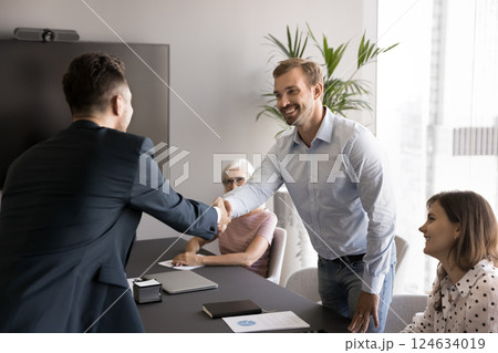 Happy business partners shaking hands at corporate meeting in office 124634019