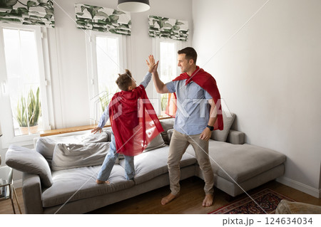 Little boy and father in cloaks sharing high five gesture Little boy and father in cloaks sharing high five gesture 124634034