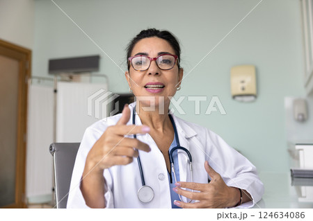 Positive mature Latin practitioner woman giving online consultation 124634086