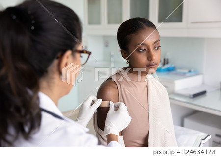 Serious depressed young Black woman visiting doctor for vaccination 124634128