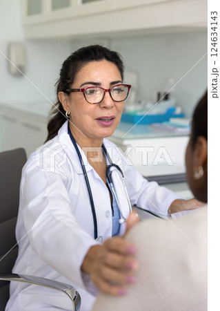 Compassionate mature doctor touching shoulder of female patient 124634143