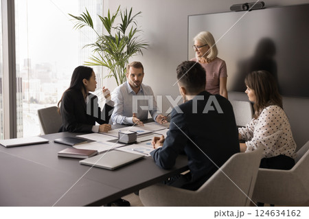 Millennial businessman addressing group of professionals seated together at table Millennial businessman addressing group of professionals seated together at table 124634162