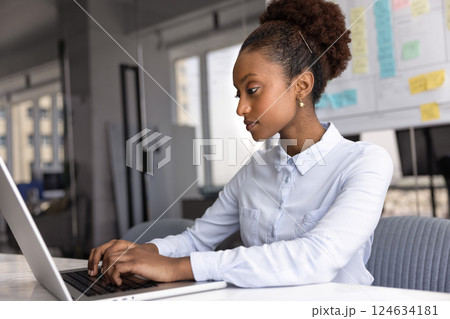 Serious young Black manager woman typing on laptop at workplace Serious young Black manager woman typing on laptop at workplace 124634181