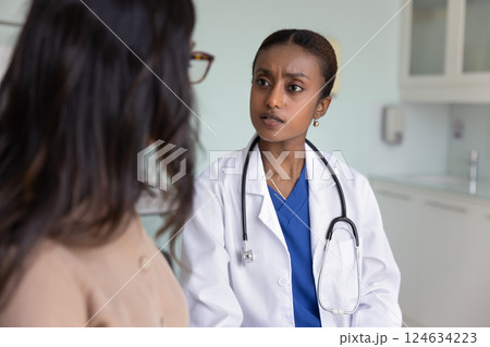 Serious young Black doctor listening to patient on checkup meeting Serious young Black doctor listening to patient on checkup meeting 124634223