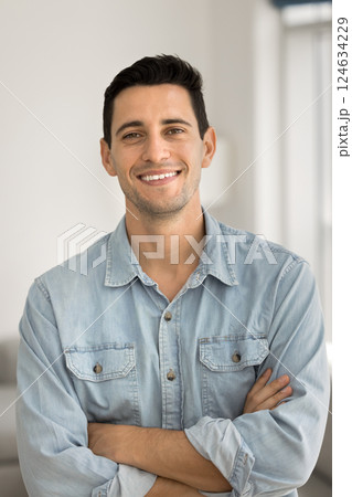 Handsome man in casual blue shirt posing indoor with arms-crossed 124634229