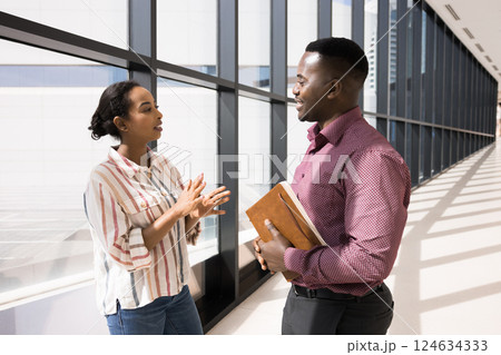 Colleagues lead talk, discussing work-related matters met in office hallway Colleagues lead talk, discussing work-related matters met in office hallway 124634333