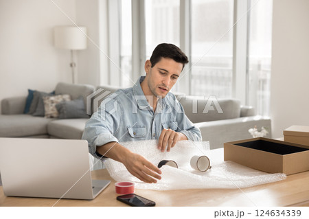 Man carefully covering mugs in bubble wrap Man carefully covering mugs in bubble wrap 124634339