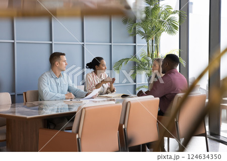 Professional team leading discussion seated at conference desk in office Professional team leading discussion seated at conference desk in office 124634350