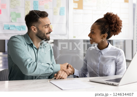 Cheerful diverse male and female business colleagues giving handshake Cheerful diverse male and female business colleagues giving handshake 124634407