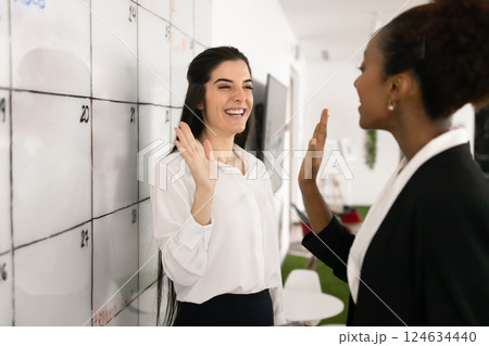 Happy multiethnic female business colleagues making high five hand gesture Happy multiethnic female business colleagues making high five hand gesture 124634440