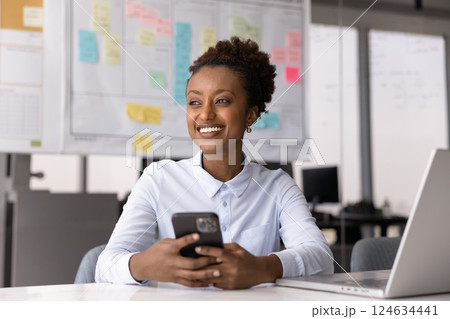 Cheerful positive young African manager woman using smartphone in office 124634441