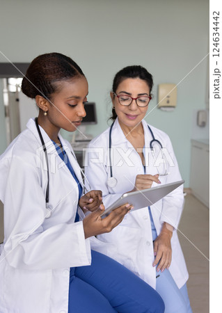 Positive senior doctor woman giving advice to young African colleague Positive senior doctor woman giving advice to young African colleague 124634442