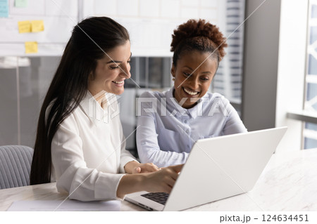 Cheerful happy diverse female business colleagues using laptop together 124634451