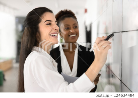 Cheerful Hispanic and African female coworkers discussing teamwork 124634494