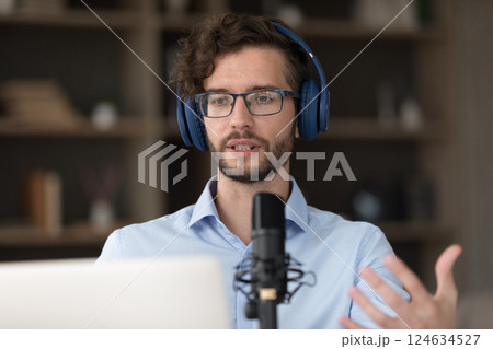 Inspired male zoomer in headset presenting speech using microphone notebook 124634527