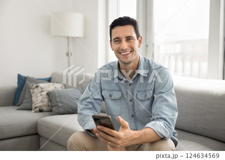 Portrait of smiling Hispanic enjoy remote communication on smartphone Portrait of smiling Hispanic enjoy remote communication on smartphone 124634569