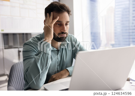 Tired annoyed Latin businessman touching head at laptop Tired annoyed Latin businessman touching head at laptop 124634596