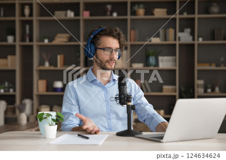 Young man in headphones speak in microphone before notebook screen 124634624