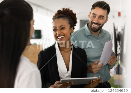 Happy diverse business partners talking at whiteboard, discussing collaboration Happy diverse business partners talking at whiteboard, discussing collaboration 124634639