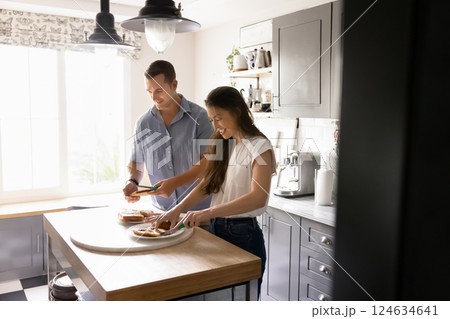 Young married couple engaged in preparing meal together Young married couple engaged in preparing meal together 124634641