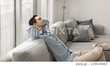 Man put his hands behind head relaxing leaned on couch Man put his hands behind head relaxing leaned on couch 124634663