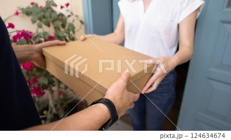 Male courier hands over packed cardboard box to recipient, closeup Male courier hands over packed cardboard box to recipient, closeup 124634674