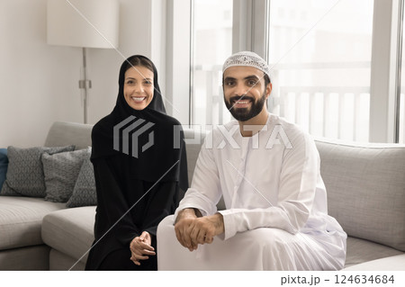 Portrait of happy Arabic family posing for camera seated indoors Portrait of happy Arabic family posing for camera seated indoors 124634684