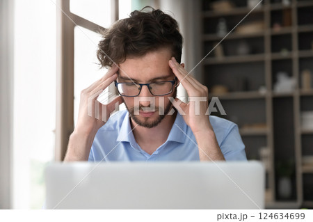 Tired young male sit by notebook close eyes rub temples Tired young male sit by notebook close eyes rub temples 124634699