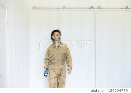 倉庫の中を歩くつなぎの男性  124634770