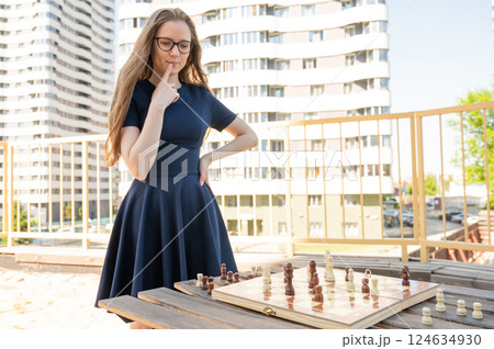 Caucasian woman playing chess outdoors. 124634930