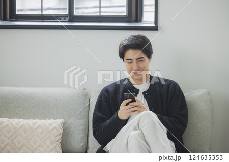 リビングでスマホを使う男性　　　 124635353