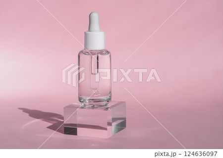 Clear Serum Dropper Bottle on Acrylic Block with Pink Background 124636097