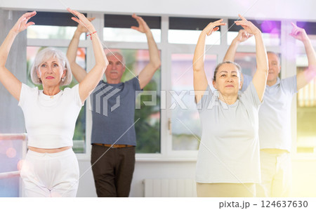 Energetic elderly woman ballet dancer executing ballet movements with group of older men and women in choreography studio Energetic elderly woman ballet dancer executing ballet movements with group of older men and women in choreography studio 124637630