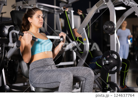 Sporty young woman using arm extension machine in gym Sporty young woman using arm extension machine in gym 124637764